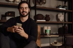A cheerful young Pakistani man holding a smartphone showing a viral video about digital assets, representing how to sell digital products in pakistan.